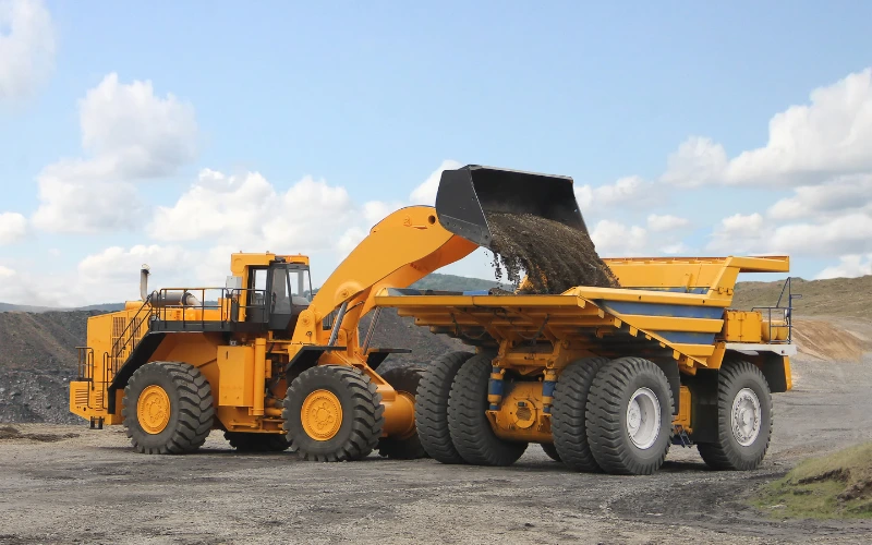 Yellow mining loader loading materials into dump truck.