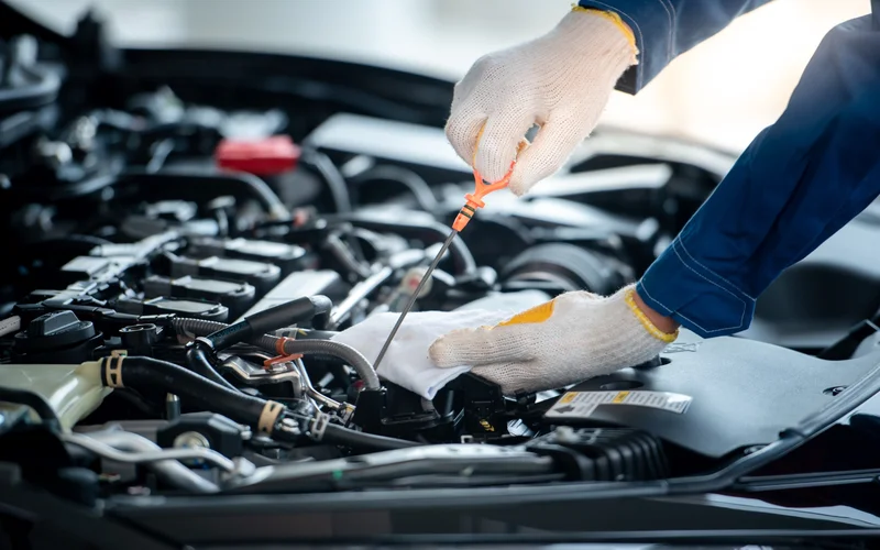 Mechanic checking oil levels on a car.