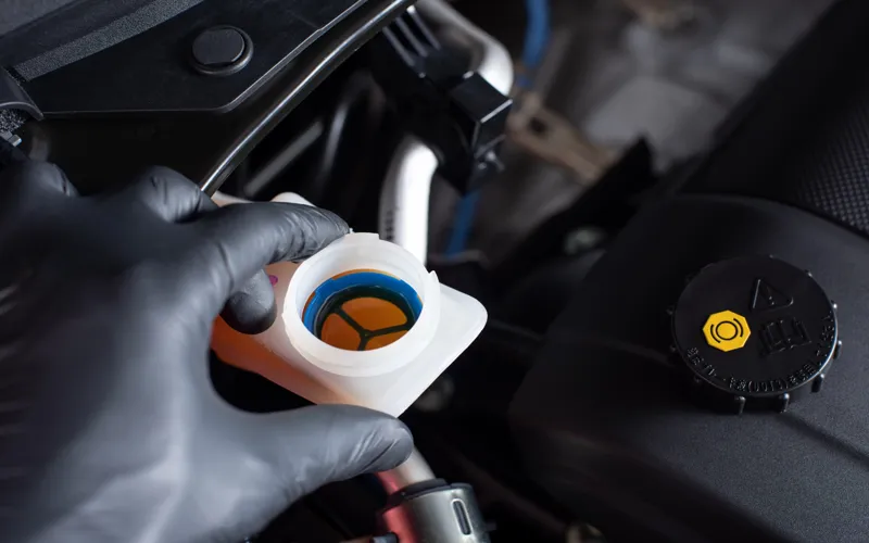 Mechanic checking brake fluid with the cap off.