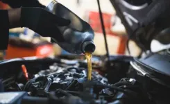 Mechanic pouring oil into car engine reservoir