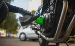 Gloved hand pouring engine oil into motorcycle engine oil reservoir.