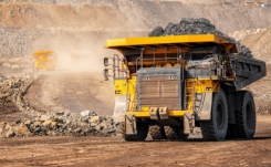 Yellow off-road dump truck driving along a dirt road thumbnail