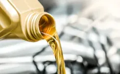Gold bottle pouring oil into car engine