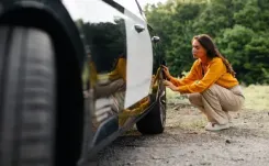 Woman checking tyre on a driveway